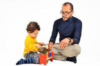 Man supervising toddler boy playing